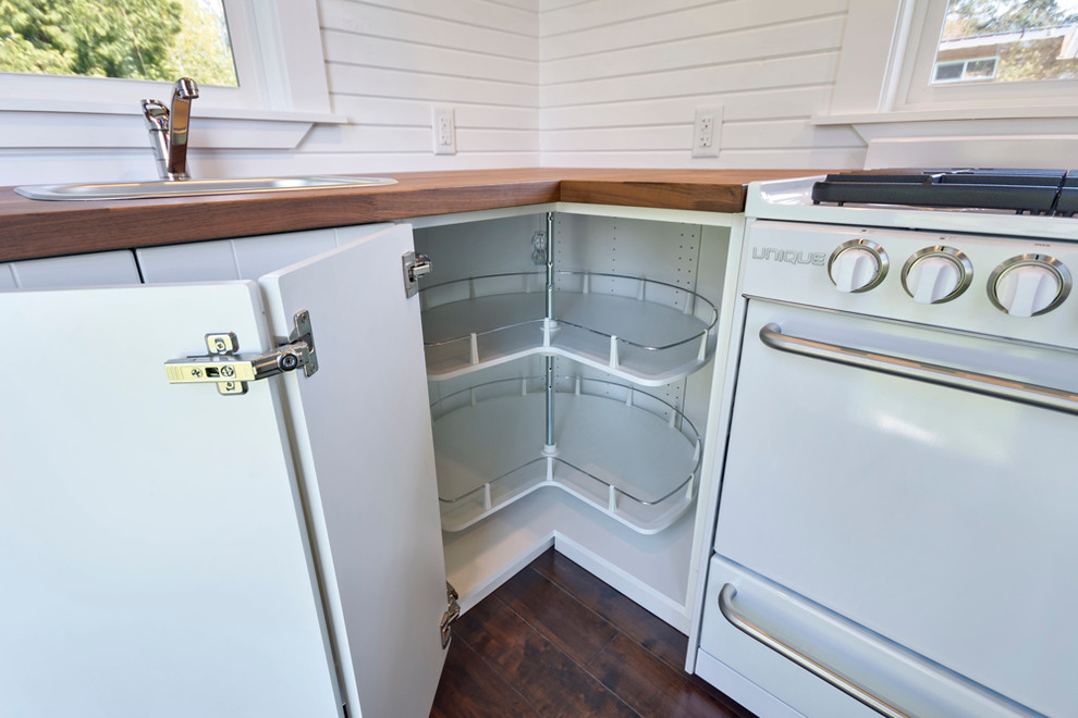 Small elegant l-shaped dark wood floor open concept kitchen photo in Vancouver with a drop-in sink, flat-panel cabinets, white cabinets, wood countertops and white appliances