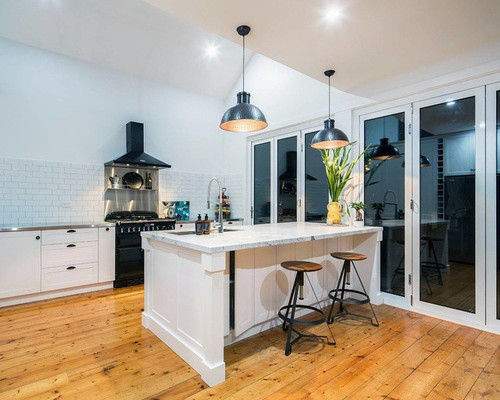 Example of a mid-sized transitional single-wall light wood floor and brown floor eat-in kitchen design with a double-bowl sink, raised-panel cabinets, white cabinets, granite countertops, stainless steel appliances and an island