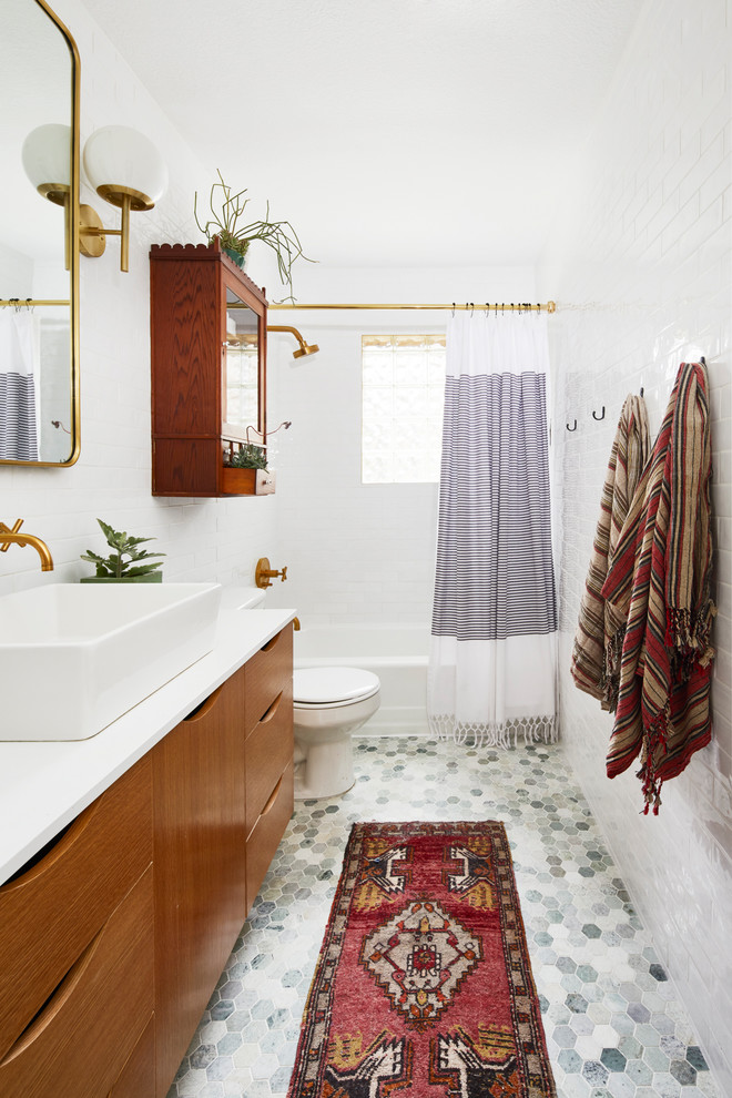 Transitional bathroom in Austin with flat-panel cabinets, medium wood cabinets, an alcove tub, a shower/bathtub combo, white tile, subway tile, white walls, mosaic tile floors, a vessel sink, grey floor, a shower curtain and white benchtops.
