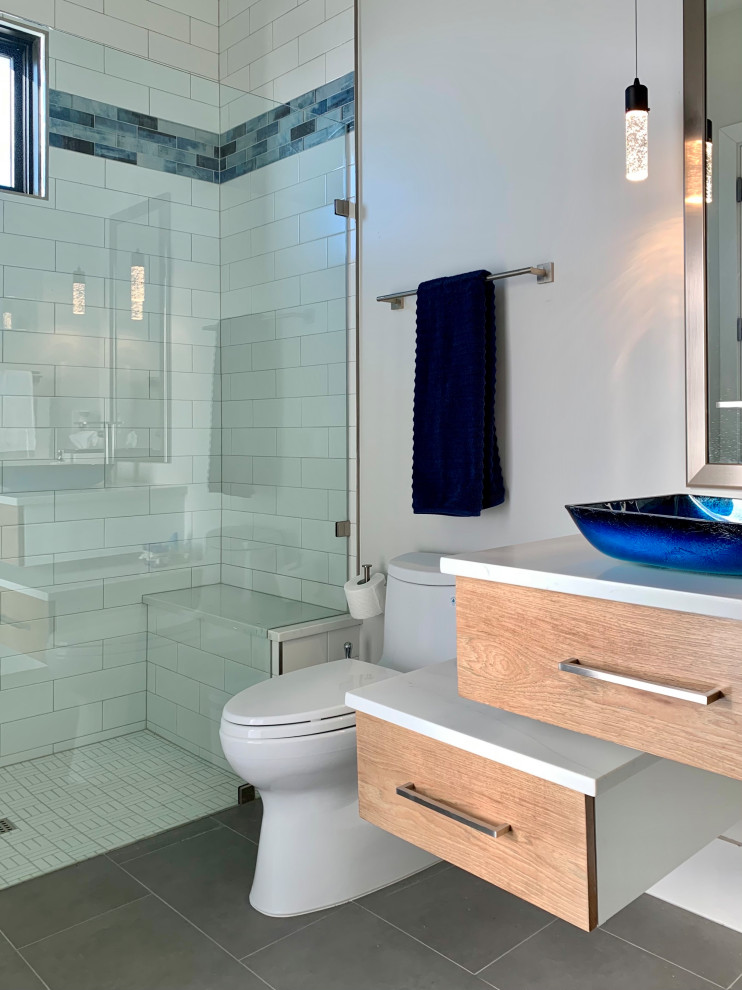 Mid-sized trendy white tile and porcelain tile porcelain tile, gray floor and single-sink bathroom photo in Dallas with flat-panel cabinets, medium tone wood cabinets, a one-piece toilet, white walls, a vessel sink, quartz countertops, a hinged shower door, white countertops and a floating vanity