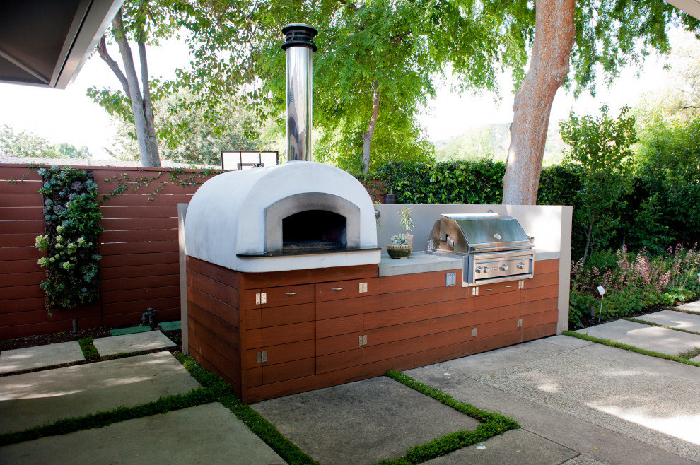 This is an example of a small contemporary backyard patio in Los Angeles with an outdoor kitchen, concrete pavers and no cover.