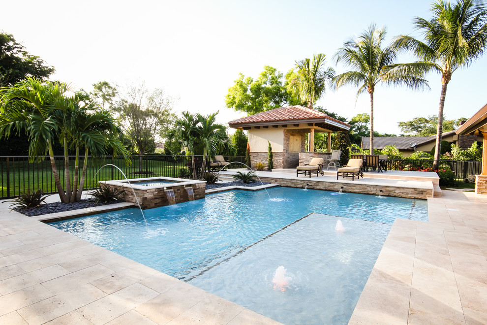 Mid-sized contemporary backyard rectangular pool in Miami with a hot tub and natural stone pavers.