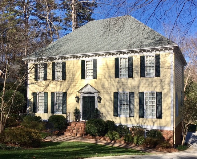This is an example of a traditional two-storey yellow house exterior in Raleigh with concrete fiberboard siding, a hip roof and a shingle roof.