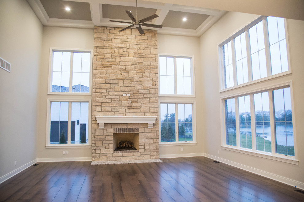 This is an example of an expansive traditional formal enclosed living room in Indianapolis with beige walls, dark hardwood floors, a standard fireplace, a stone fireplace surround, brown floor and coffered.