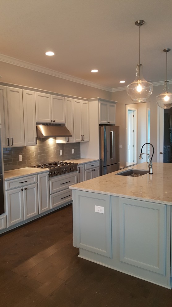 Eat-in kitchen - large galley light wood floor and brown floor eat-in kitchen idea in Tampa with a drop-in sink, flat-panel cabinets, white cabinets, granite countertops, gray backsplash, ceramic backsplash, stainless steel appliances and an island