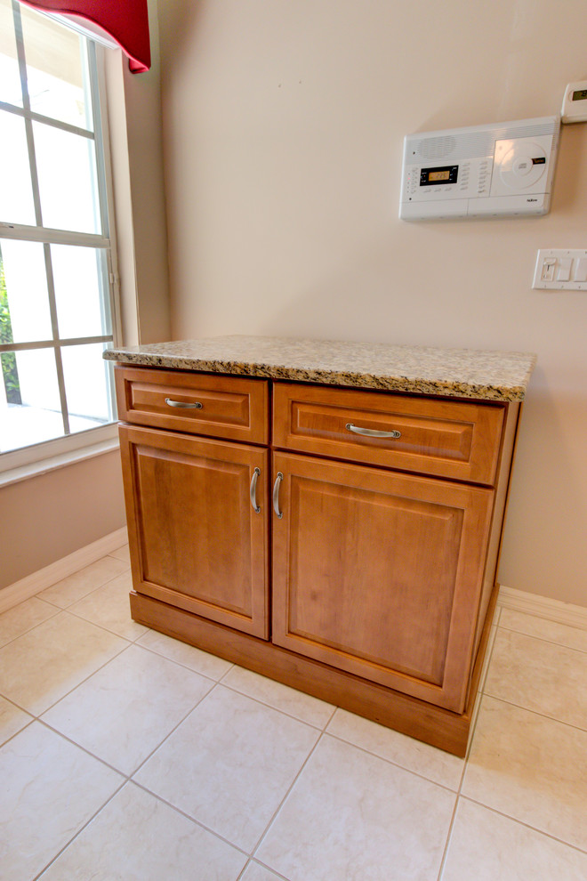 Example of a mid-sized kitchen design with an undermount sink, raised-panel cabinets, medium tone wood cabinets, granite countertops, white appliances and brown countertops