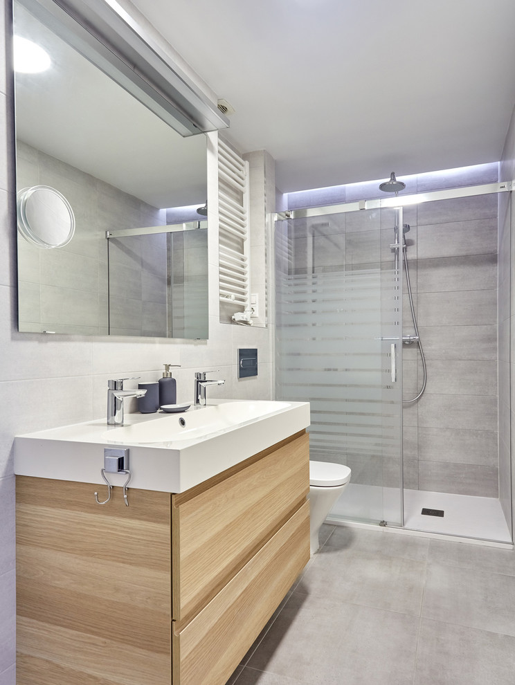 Photo of a mid-sized scandinavian master bathroom in Other with a curbless shower, a wall-mount toilet, gray tile, ceramic tile, grey walls, porcelain floors, a trough sink, grey floor and a sliding shower screen.