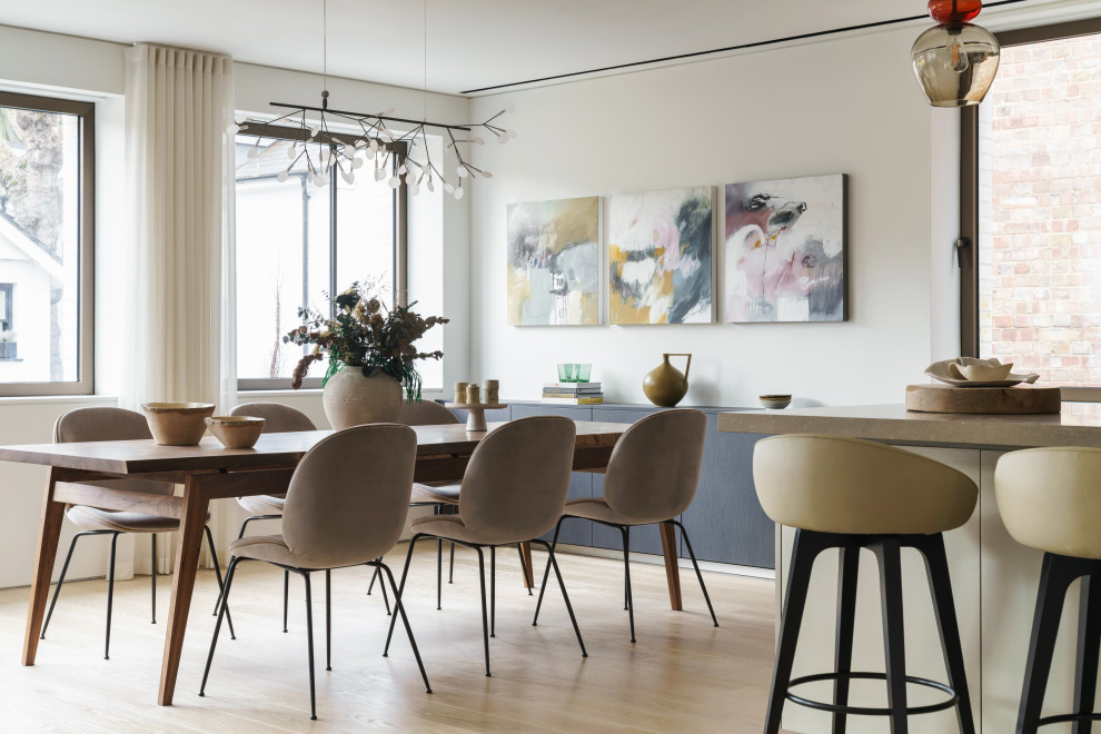 This is an example of a mid-sized contemporary open plan dining in London with white walls, light hardwood floors and beige floor.