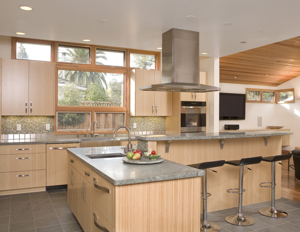 This is an example of a mid-sized contemporary u-shaped kitchen in San Francisco with mosaic tile splashback, stainless steel appliances, green splashback, light wood cabinets, flat-panel cabinets, an undermount sink, multiple islands, ceramic floors and grey floor.