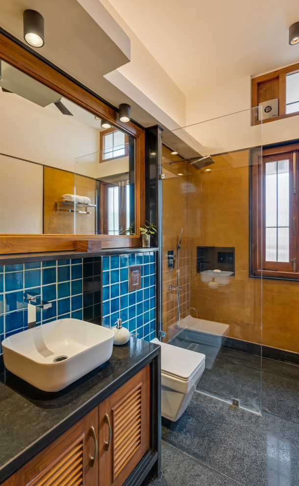 Exempel på ett stort modernt svart svart en-suite badrum, med luckor med lamellpanel, skåp i mellenmörkt trä, en hörndusch, en vägghängd toalettstol, blå kakel, keramikplattor, flerfärgade väggar, marmorgolv, ett konsol handfat, granitbänkskiva, grått golv och med dusch som är öppen