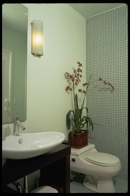 Inspiration for a mid-sized contemporary bathroom in San Francisco with a vessel sink, furniture-like cabinets, dark wood cabinets, a corner tub, a shower/bathtub combo, a one-piece toilet, green tile, glass tile, green walls and porcelain floors.