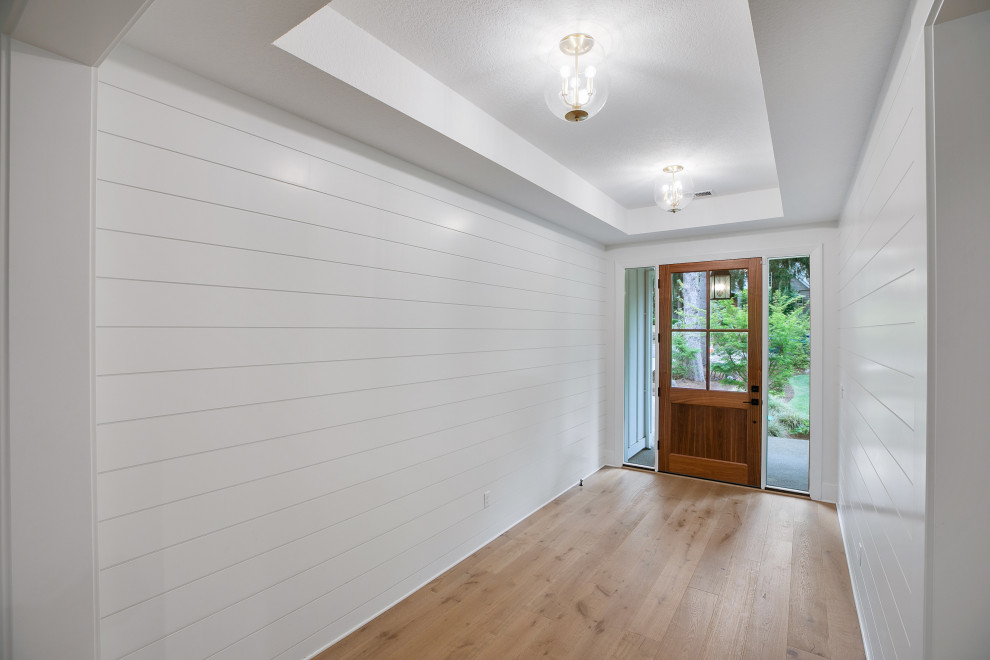 ポートランドにある低価格の中くらいなミッドセンチュリースタイルのおしゃれな玄関ロビー (白い壁、淡色無垢フローリング、木目調のドア、ベージュの床) の写真