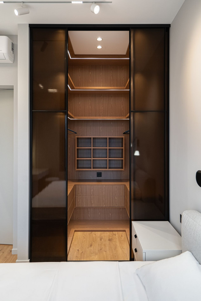 Design ideas for a mid-sized contemporary gender-neutral walk-in wardrobe in Moscow with flat-panel cabinets, medium wood cabinets and medium hardwood floors.