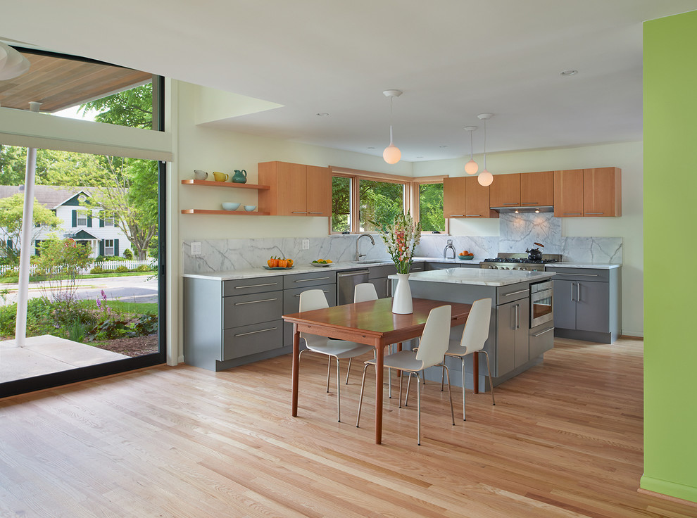 Design ideas for a mid-sized midcentury l-shaped eat-in kitchen in DC Metro with an undermount sink, flat-panel cabinets, grey cabinets, marble benchtops, white splashback, stone slab splashback, stainless steel appliances, light hardwood floors and with island.