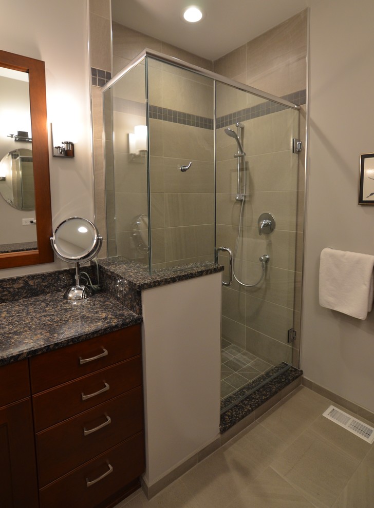 Photo of a small transitional bathroom in Other with flat-panel cabinets, medium wood cabinets, a drop-in tub, an alcove shower, a two-piece toilet, gray tile, porcelain tile, grey walls, porcelain floors, an undermount sink and granite benchtops.