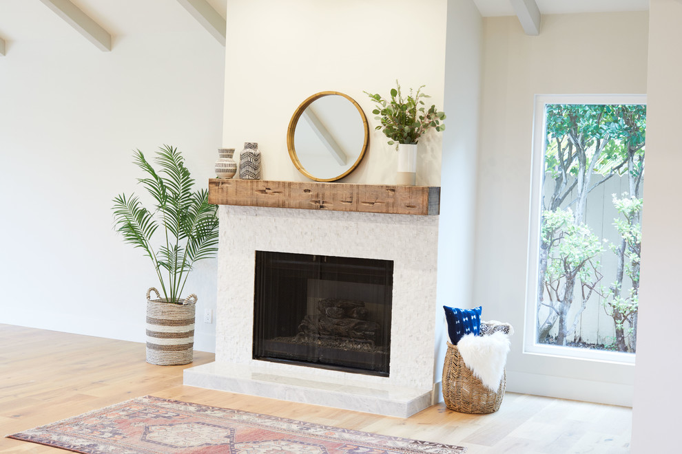 This is an example of a large country formal open concept living room in San Diego with white walls, light hardwood floors, a standard fireplace, a tile fireplace surround and beige floor.