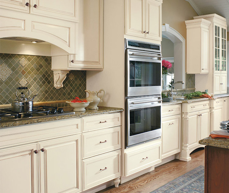 Inspiration for a mid-sized transitional l-shaped dark wood floor and brown floor eat-in kitchen remodel in Orange County with an undermount sink, white cabinets, granite countertops, beige backsplash, ceramic backsplash, stainless steel appliances, an island and raised-panel cabinets
