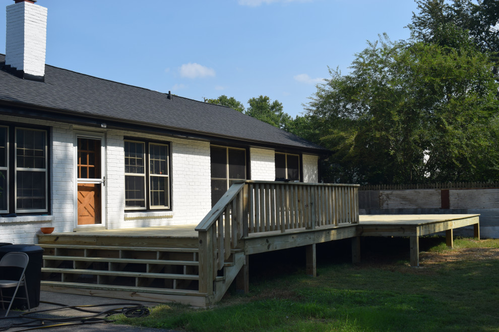 Inspiration for a large backyard ground level wood railing deck remodel with a roof extension
