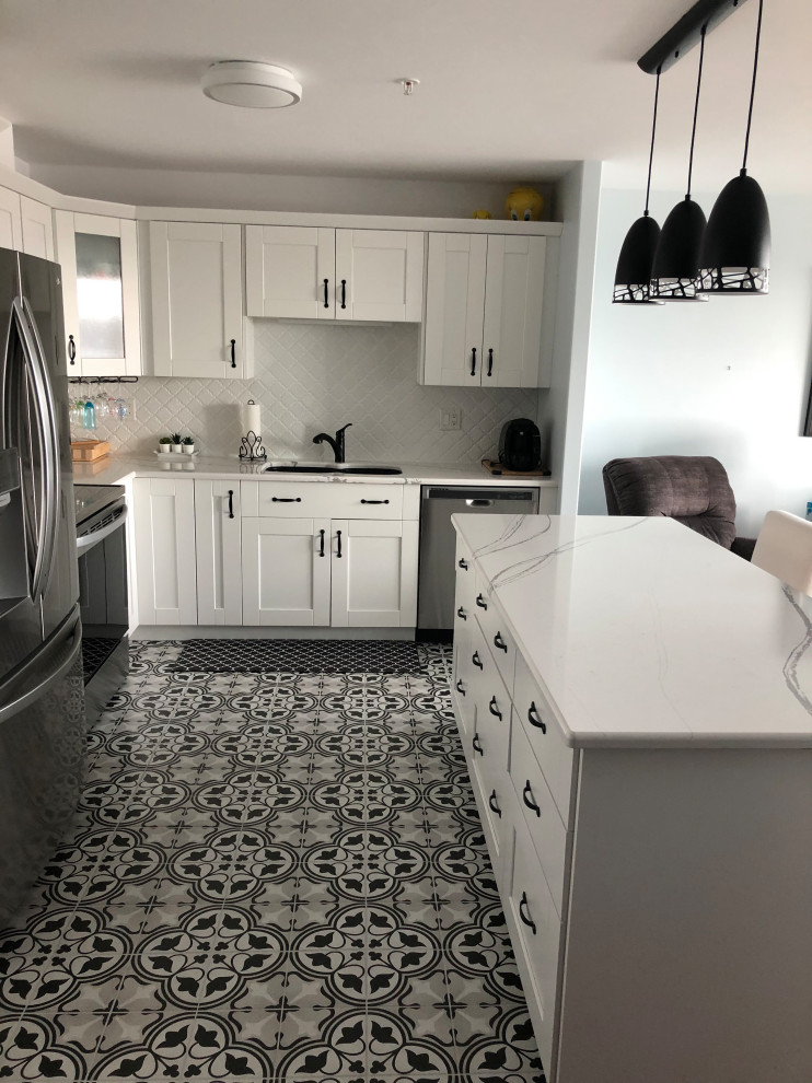 Inspiration for a mid-sized transitional l-shaped ceramic tile and black floor eat-in kitchen remodel with an undermount sink, shaker cabinets, white cabinets, quartz countertops, white backsplash, ceramic backsplash, stainless steel appliances, an island and white countertops
