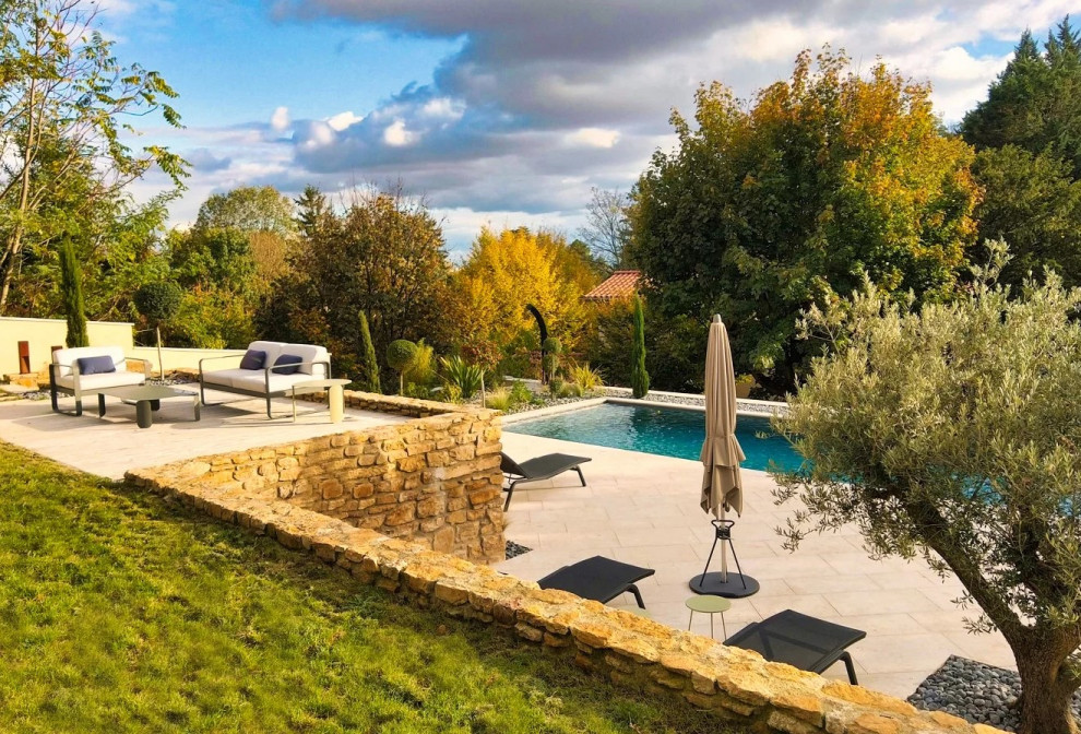 Photo of a large transitional front yard rectangular infinity pool in Lyon with natural stone pavers.