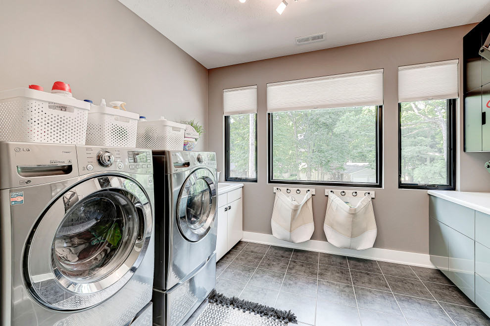 Dedicated laundry room - mid-sized contemporary u-shaped ceramic tile and gray floor dedicated laundry room idea in Indianapolis with a drop-in sink, shaker cabinets, gray cabinets, laminate countertops, gray walls, a side-by-side washer/dryer and white countertops