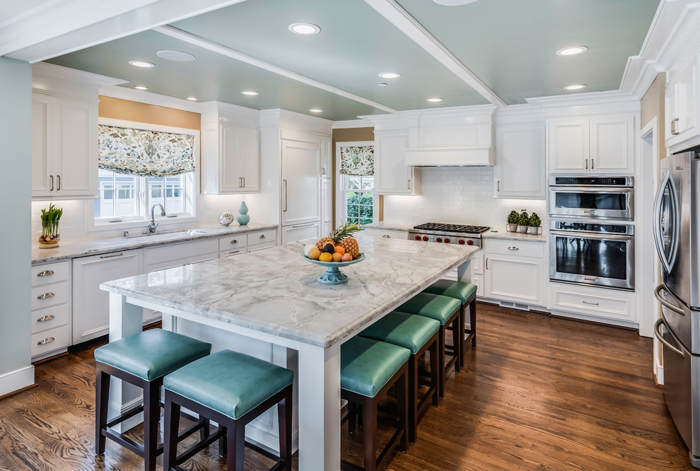 This is an example of a traditional u-shaped kitchen in Sacramento with a single-bowl sink, recessed-panel cabinets, white cabinets, marble benchtops, stainless steel appliances, dark hardwood floors, with island and grey benchtop.