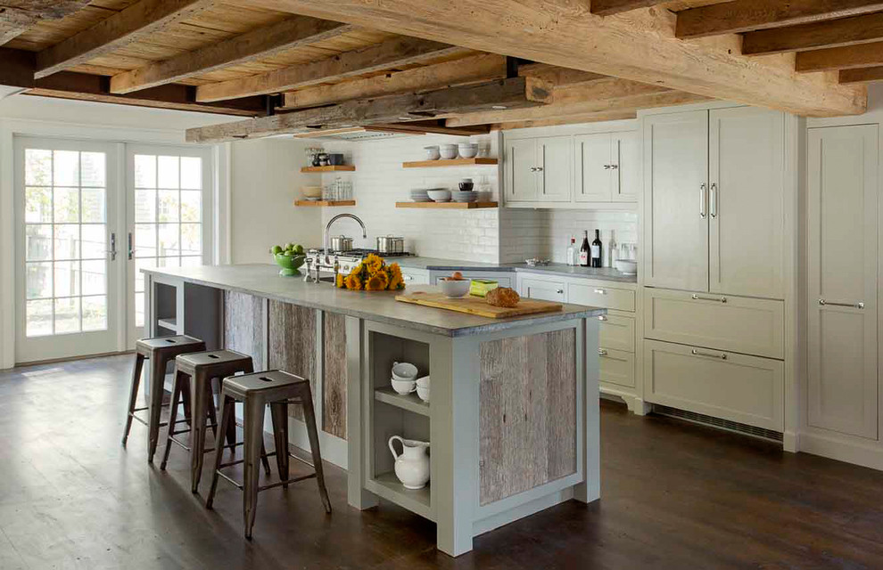 This is an example of a small country galley eat-in kitchen in Boston with a farmhouse sink, recessed-panel cabinets, grey cabinets, soapstone benchtops, white splashback, ceramic splashback, stainless steel appliances, dark hardwood floors and with island.