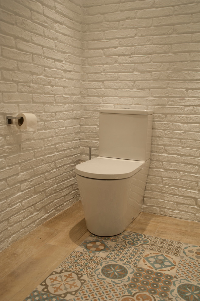 Modelo de aseo escandinavo de tamaño medio con sanitario de dos piezas, paredes blancas, suelo de baldosas de cerámica y lavabo suspendido
