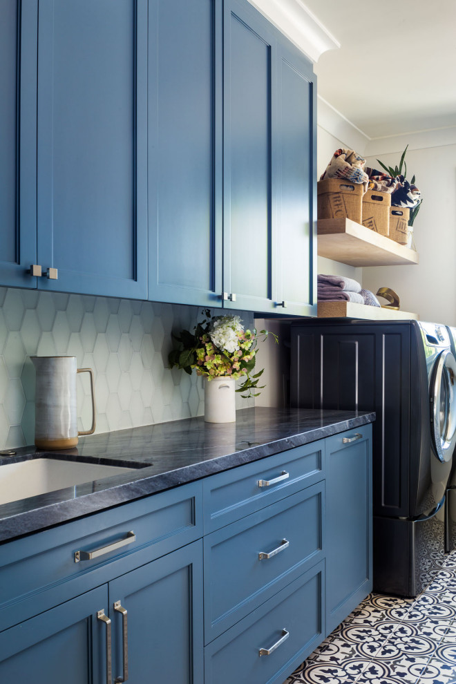 Einzeilige, Große Klassische Waschküche mit Unterbauwaschbecken, Schrankfronten im Shaker-Stil, blauen Schränken, Marmor-Arbeitsplatte, bunten Wänden, Porzellan-Bodenfliesen, Waschmaschine und Trockner nebeneinander, blauem Boden und schwarzer Arbeitsplatte in San Francisco