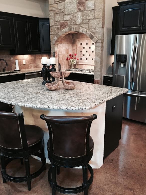 Inspiration for a mid-sized rustic l-shaped concrete floor eat-in kitchen remodel in Austin with an undermount sink, raised-panel cabinets, black cabinets, granite countertops, beige backsplash, ceramic backsplash, stainless steel appliances and an island