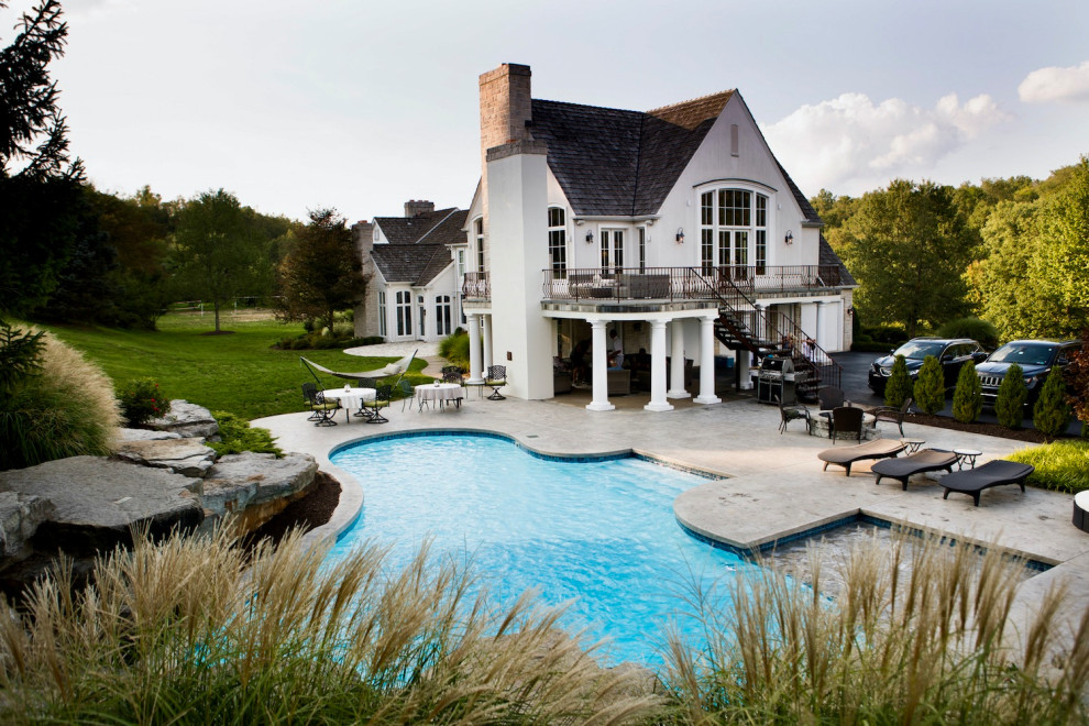 Large transitional backyard custom-shaped pool in Other with stamped concrete.