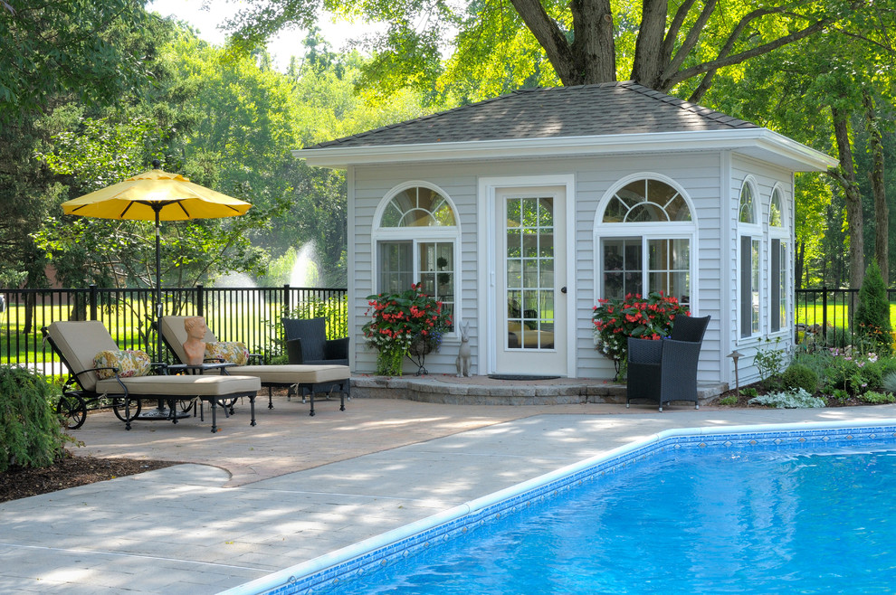 Photo of a large traditional backyard custom-shaped pool in Bridgeport with a pool house and concrete pavers.
