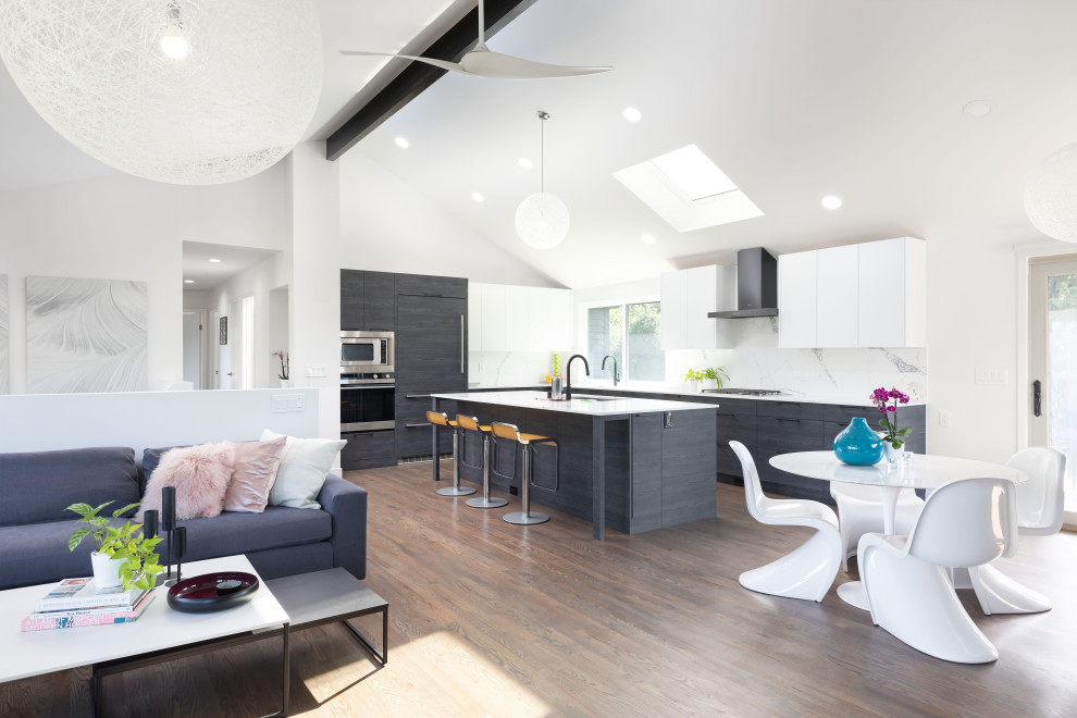 Inspiration for a contemporary l-shaped dark wood floor, brown floor and vaulted ceiling eat-in kitchen remodel in Seattle with a single-bowl sink, flat-panel cabinets, black cabinets, quartz countertops, white backsplash, quartz backsplash, paneled appliances, an island and white countertops