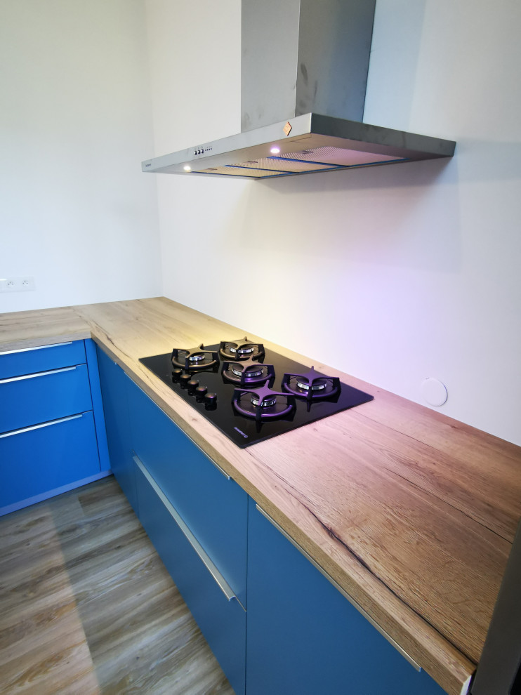 Idée de décoration pour cuisine in L With un évier 2 bacs, un placard à porte affleurante, des portes de placard bleues, un plan de travail en bois, parquet clair, îlot, un sol marron and un plan de travail marron.
