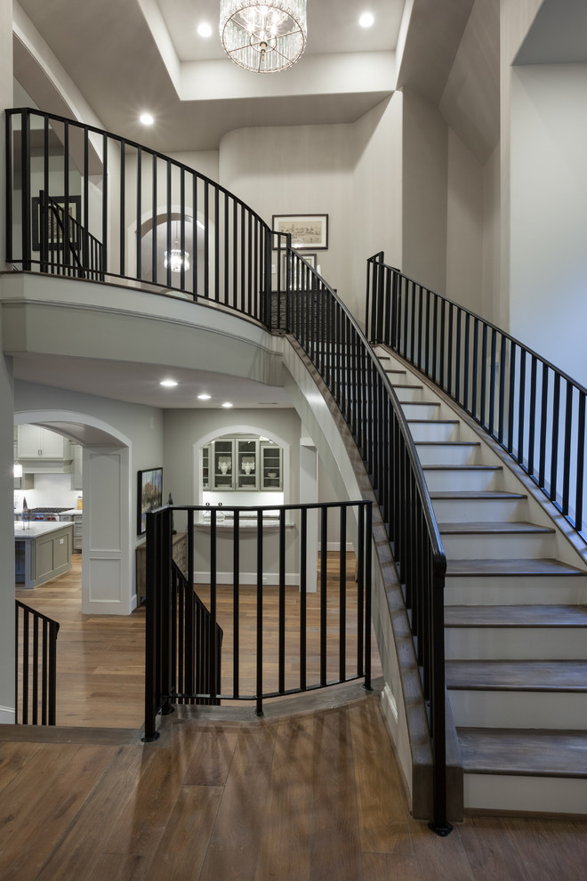 Expansive transitional wood u-shaped staircase in Houston with wood risers and metal railing.