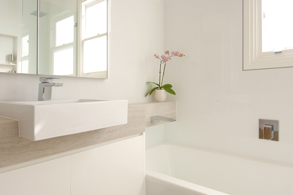 Идея дизайна: главная ванная комната среднего размера в стиле модернизм с плоскими фасадами, белыми фасадами, накладной ванной, душем в нише, унитазом-моноблоком, белой плиткой, керамической плиткой, белыми стенами, полом из известняка, настольной раковиной, столешницей из известняка, бежевым полом, открытым душем, бежевой столешницей, нишей, тумбой под одну раковину, подвесной тумбой, многоуровневым потолком и панелями на стенах