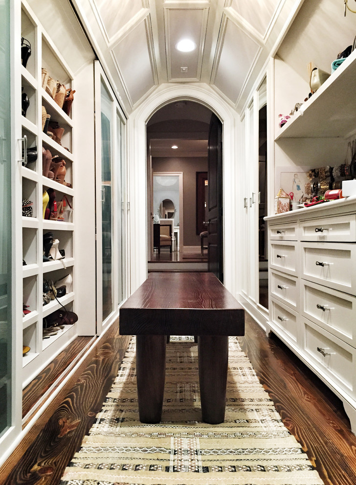 Photo of a traditional women's walk-in wardrobe in New Orleans with shaker cabinets, white cabinets and dark hardwood floors.
