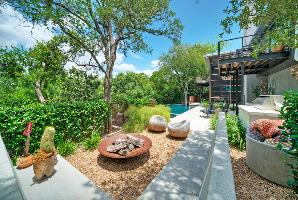 Large contemporary backyard shaded xeriscape in Austin with with path and natural stone pavers for spring.