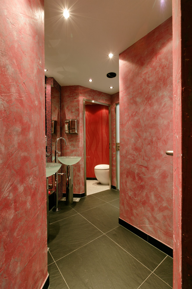Idée de décoration pour un très grand WC suspendu asiatique avec un carrelage rouge, un carrelage en pâte de verre, un mur noir, un sol en ardoise, un plan vasque, un plan de toilette en verre, un sol noir, meuble-lavabo sur pied et un plafond décaissé.