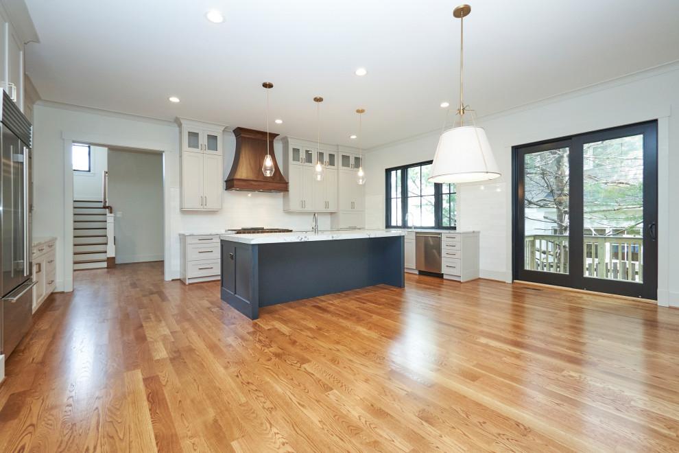 Large transitional u-shaped medium tone wood floor and brown floor open concept kitchen photo in DC Metro with an undermount sink, shaker cabinets, beige cabinets, quartz countertops, white backsplash, marble backsplash, stainless steel appliances, an island and white countertops