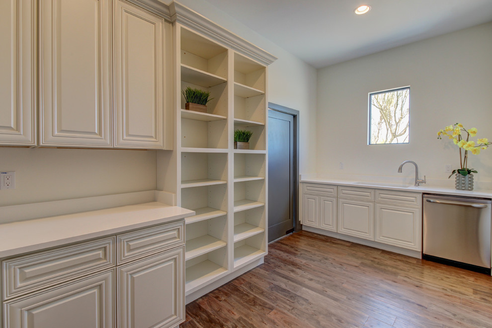 Eat-in kitchen - mid-sized transitional l-shaped dark wood floor and brown floor eat-in kitchen idea in Phoenix with a farmhouse sink, raised-panel cabinets, white cabinets, marble countertops, white backsplash, subway tile backsplash, stainless steel appliances and an island