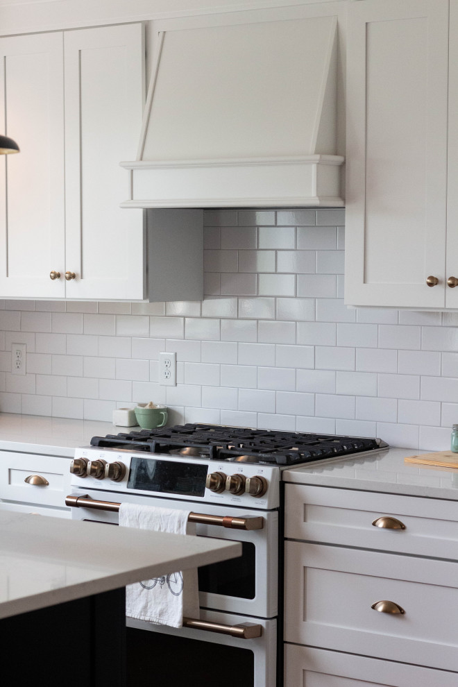 Inspiration for a mid-sized transitional l-shaped medium tone wood floor and brown floor open concept kitchen remodel with an undermount sink, shaker cabinets, white cabinets, quartzite countertops, white backsplash, ceramic backsplash, white appliances, an island and white countertops