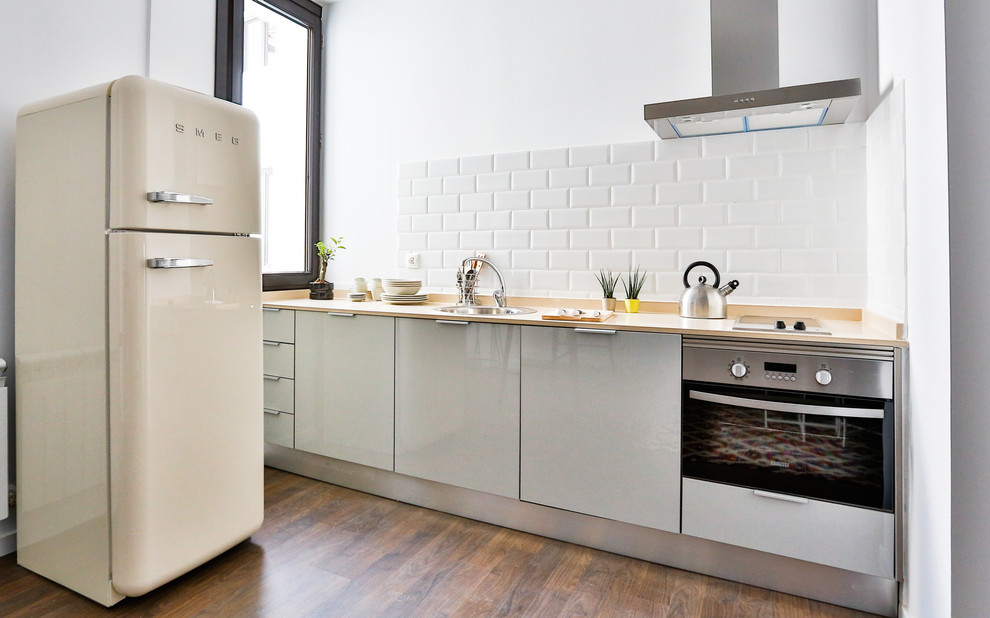 This is an example of a small scandinavian single-wall open plan kitchen in Madrid with an undermount sink, flat-panel cabinets, grey cabinets, quartz benchtops, white splashback, subway tile splashback, panelled appliances, dark hardwood floors and no island.