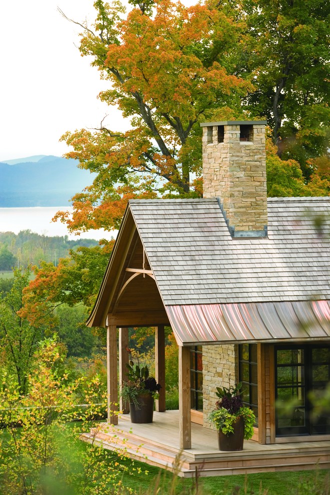 Design ideas for a country one-storey exterior in Burlington with stone veneer, a gable roof and a mixed roof.