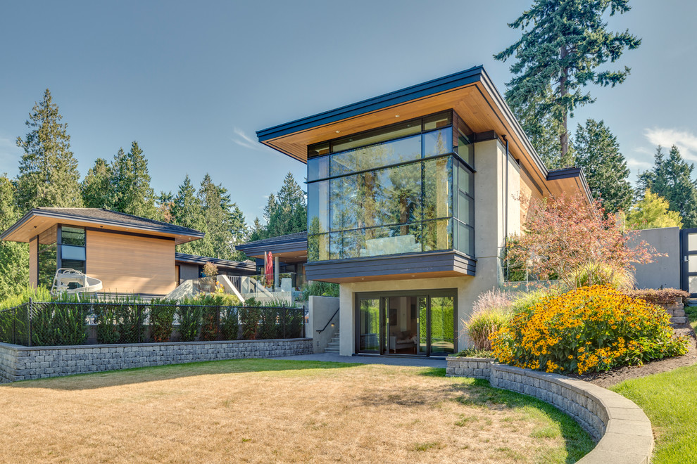 This is an example of a large contemporary two-storey concrete beige house exterior in Vancouver with a flat roof and a shingle roof.