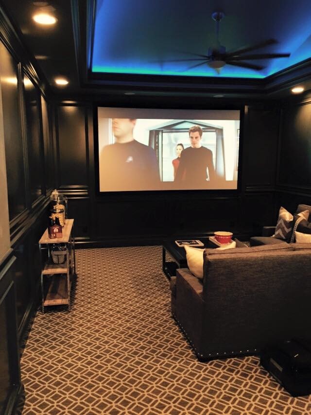 Inspiration for a mid-sized traditional enclosed home theatre in Austin with brown walls, carpet, a projector screen and brown floor.