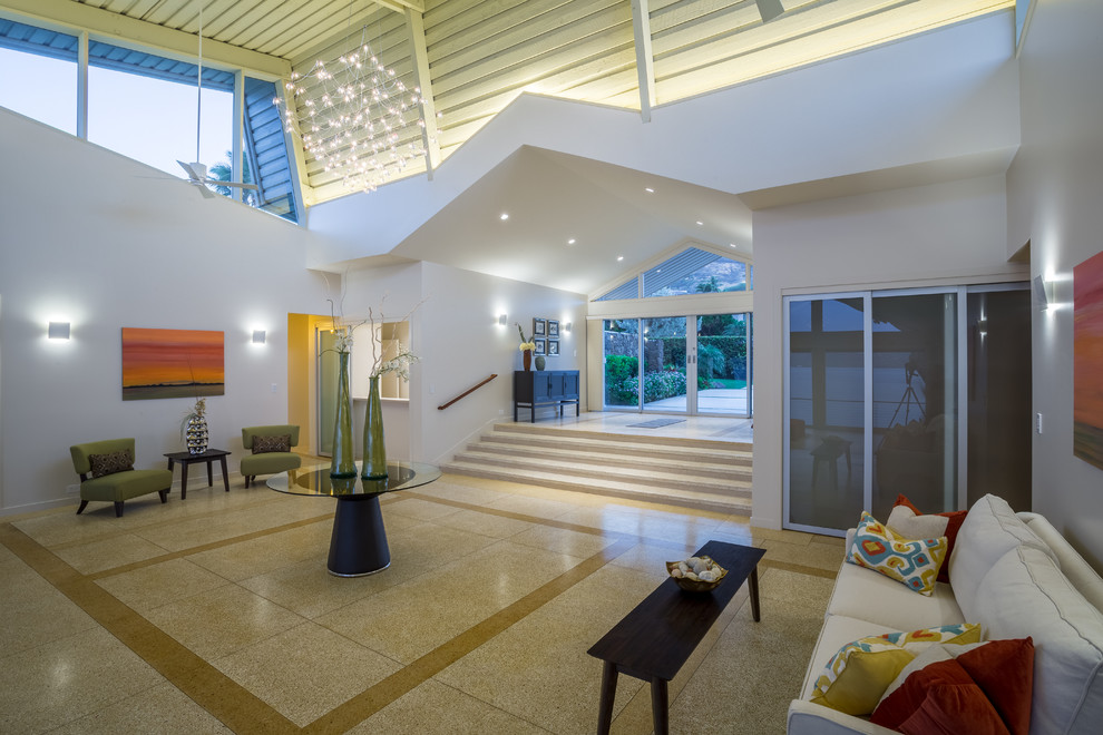 Photo of a large contemporary foyer in Hawaii with white walls, porcelain floors, a glass front door and beige floor.