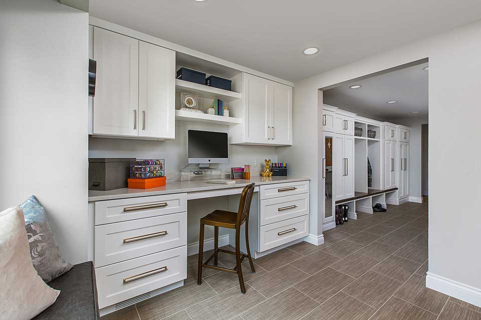 デトロイトにある広いトランジショナルスタイルのおしゃれな家事室 (ll型、アンダーカウンターシンク、落し込みパネル扉のキャビネット、白いキャビネット、クオーツストーンカウンター、グレーの壁、磁器タイルの床、左右配置の洗濯機・乾燥機、ベージュの床、ベージュのキッチンカウンター、白いキッチンパネル、木材のキッチンパネル、白い天井) の写真