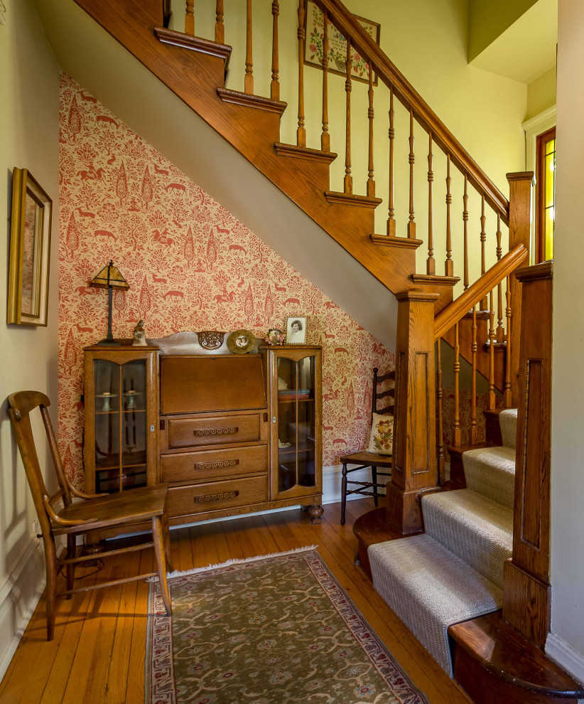 Mid-sized traditional carpeted u-shaped staircase in Chicago with wood risers, wood railing and wallpaper.