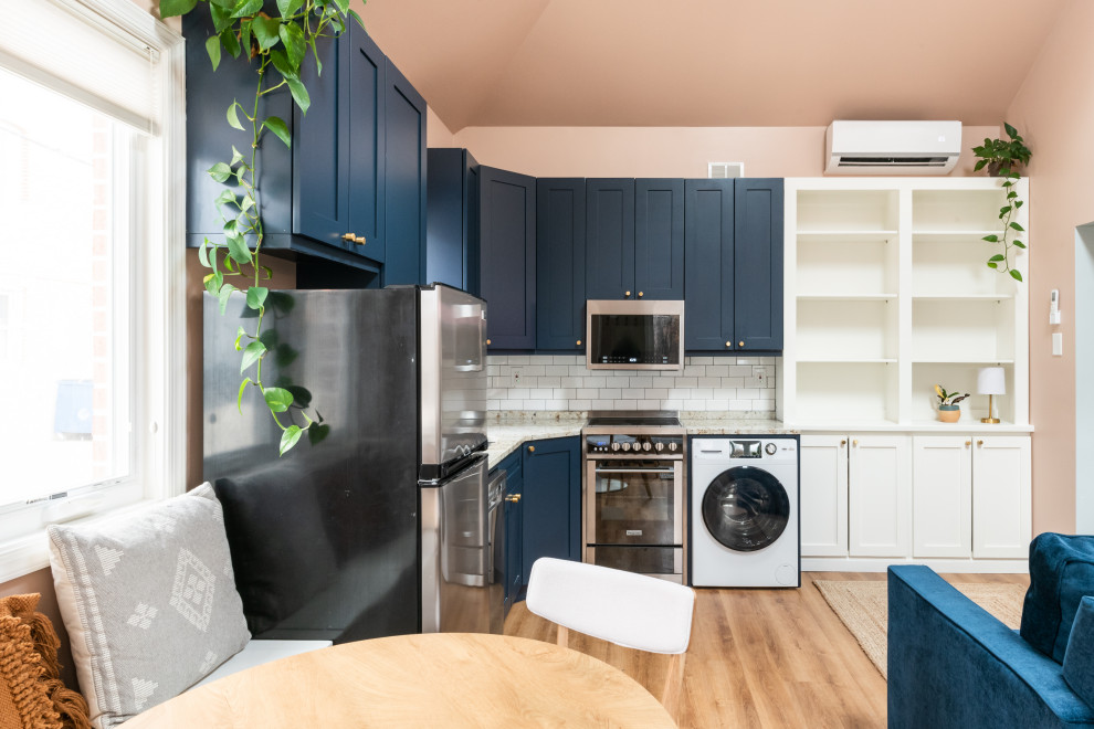 Small contemporary l-shaped eat-in kitchen in DC Metro with an undermount sink, recessed-panel cabinets, blue cabinets, granite benchtops, white splashback, subway tile splashback, stainless steel appliances, linoleum floors, beige floor, grey benchtop and vaulted.